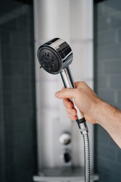 A man's hand holds the watering can from the shower. Modern plumbing for the bathroom and shower