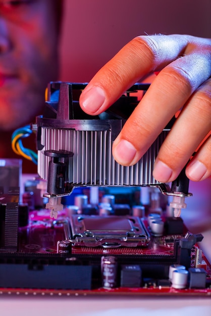 A man's hand inserts a cooler into the motherboard socket