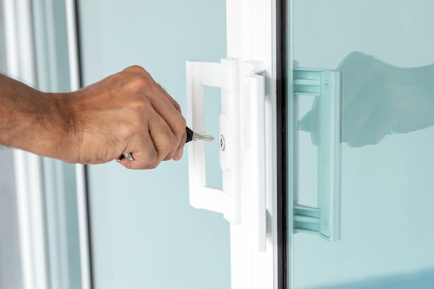 Man's hand opening a glass door with a key