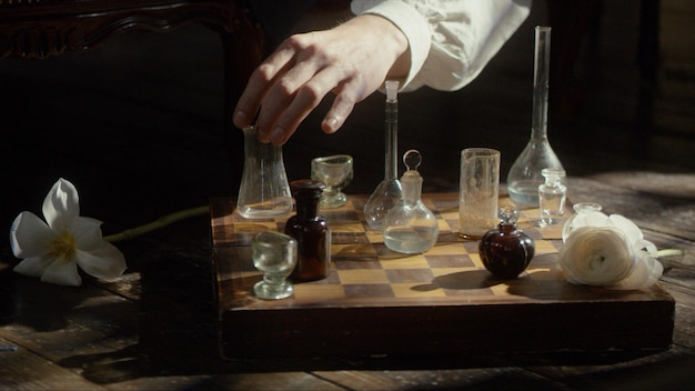 A man's hand plays chess with flasks on a chessboard premium photo