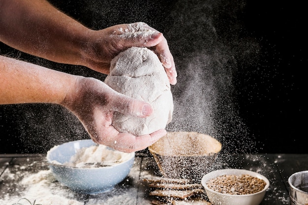 Man's hand preparing dough with ingredients on the table