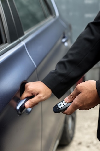 Man's hand pressing on the car remote key while holding hand pull to open the car door