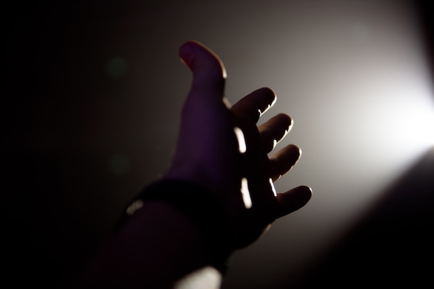 Man's hand in a ray of light on a black