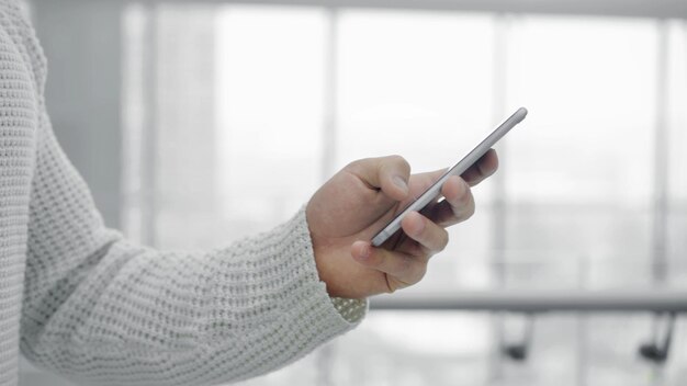 Photo man s hand scrolling a phone on blurred yellow background