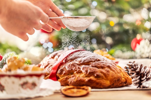 Man's hand sprinkling icing sugar over fresh christmas cake Vanocka