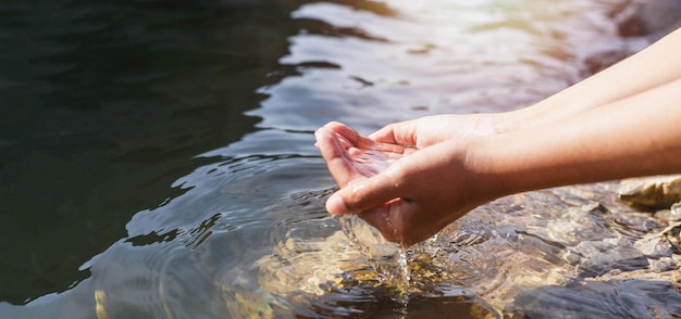 Man's hand touching water in the midst of nature