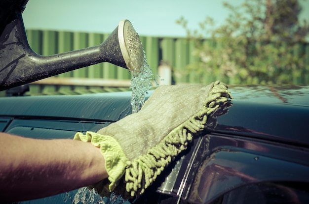 a man's hand washes the car