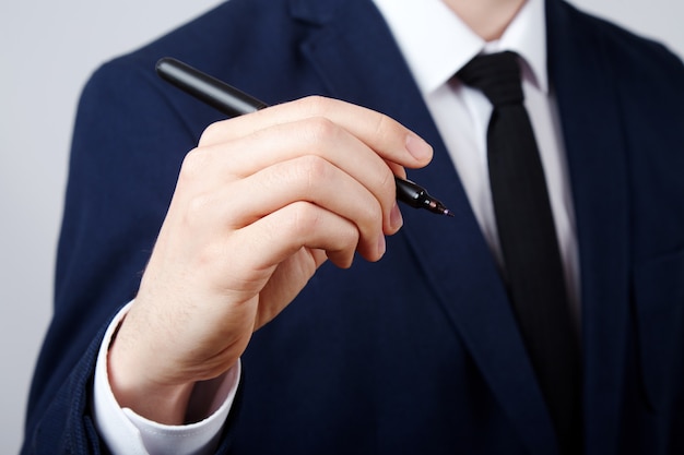 Man's hand wearing white shirt and suit  wall, close up, business concept, holding a pen, writing.