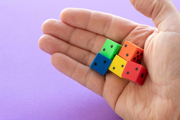 Man's hand with five dice of different colors on a purple background