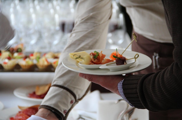 Man's hand with a plate of appetizers at the catering table