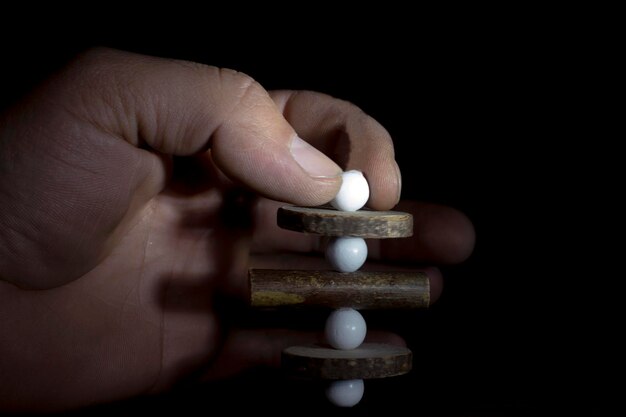 man 's hand with wooden tablets and a white pill