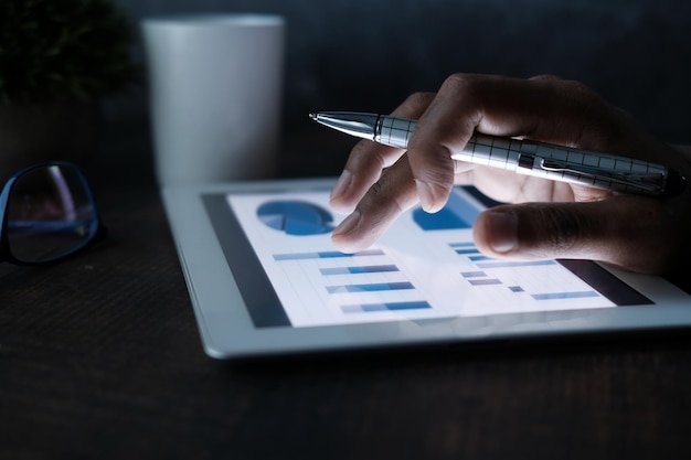 man's hand working on digital tablet at office desk using self created chart