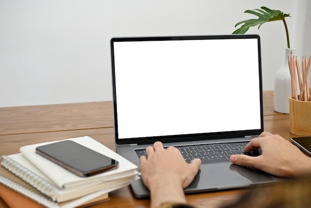 A man's hands are typing on a laptop keyboard using a laptop notebook laptop white screen mockup