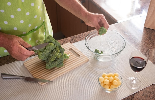 Man's hands cut the broccoli into small pieces Preparation of a healthy dish Red wine glass in the corner