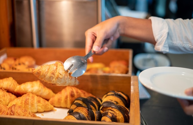 Man's hands holding bread with tongs in a bread shop croissants bread breakfast