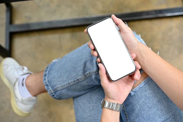 A man's hands holding a smartphone over his lap phone white screen mockup