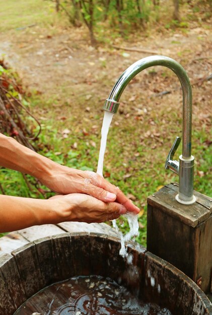 Man's hands under the running water from the faucet in the garden