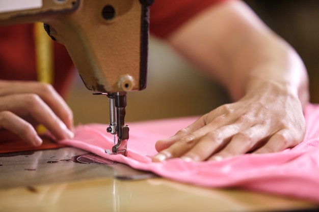 Man's hands sewing on a sewinghine at a clothing factory