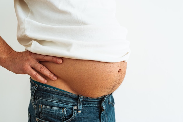 A man's stomach is shown with a white shirt on.