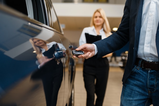 Man and saleswoman choosing auto in car dealership. Customer and seller in vehicle showroom, male person buying transport, automobile dealer business