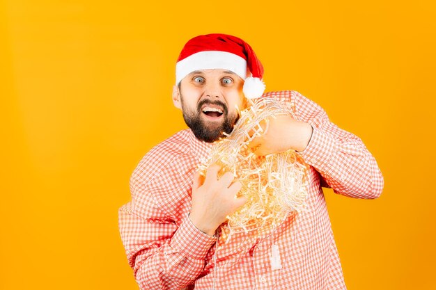 A man in a Santa Claus hat holds a garland in his hands