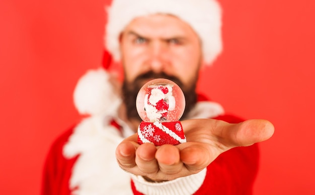 Man in santa costume with small snow globe christmas snow globe new year and christmas decorations