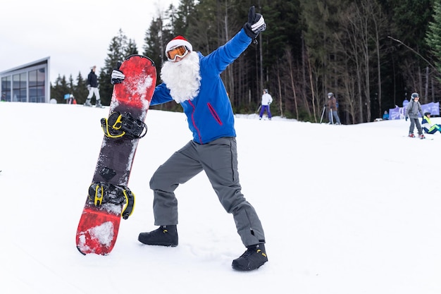 a man in a santa hat with a snowboard at a ski resort.