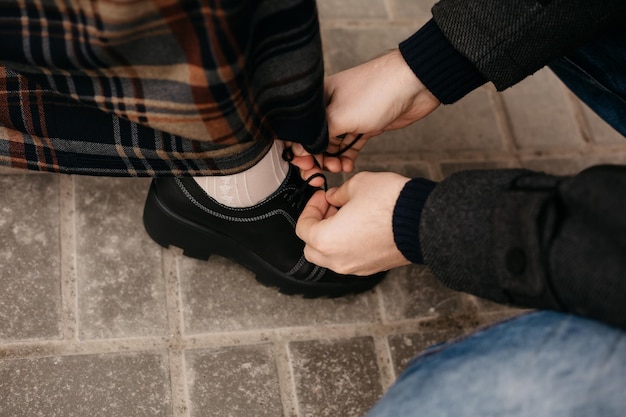 Man sat down and helps to tie the woman's shoelaces. Assistance to a person with limited mobility.