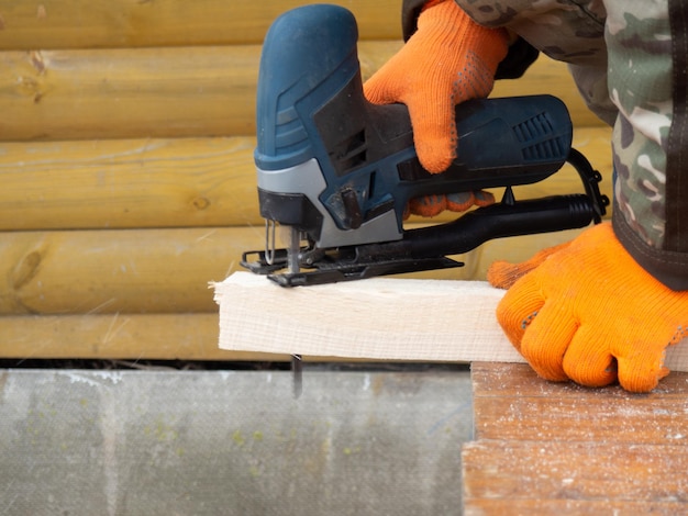 A man saws timber with an electric jigsaw construction and repair in a country house