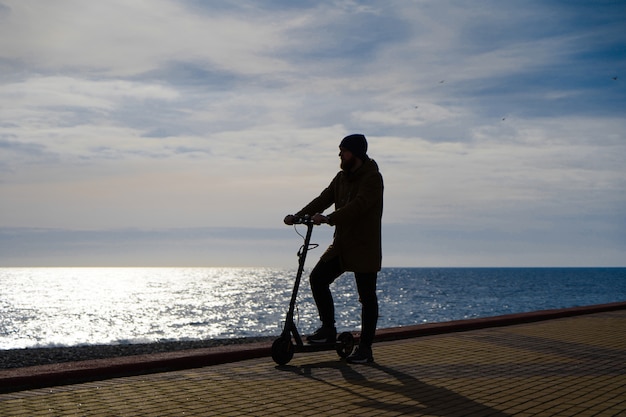 Man on scooter at sunset, silhouette, free space