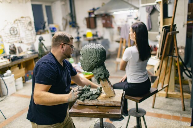 Man sculptor creates sculpt bust clay human woman sculpture Statue craft creation workshop