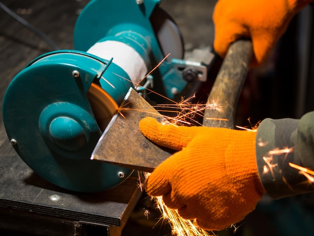 Man sharpening an ax blade on a grinder