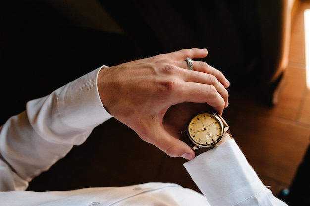 A man in a shirt adjusts the watch on his arm Close up of businessman using watch flat lay top view