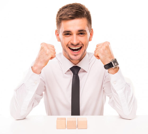 A man in a shirt and tie rejoices raising his hands.