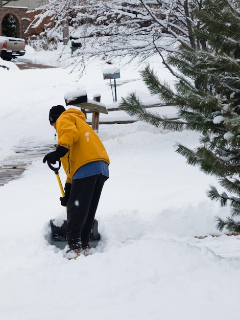 A man shoceling his sidewalk.