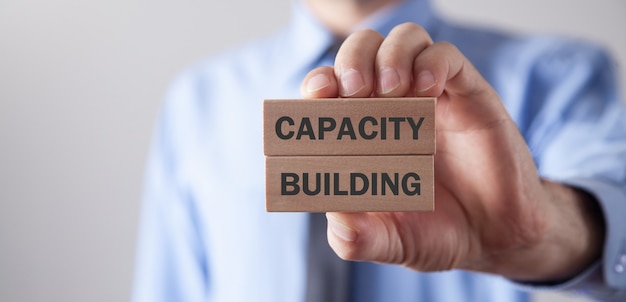 Man showing Capacity Building text on wooden blocks.