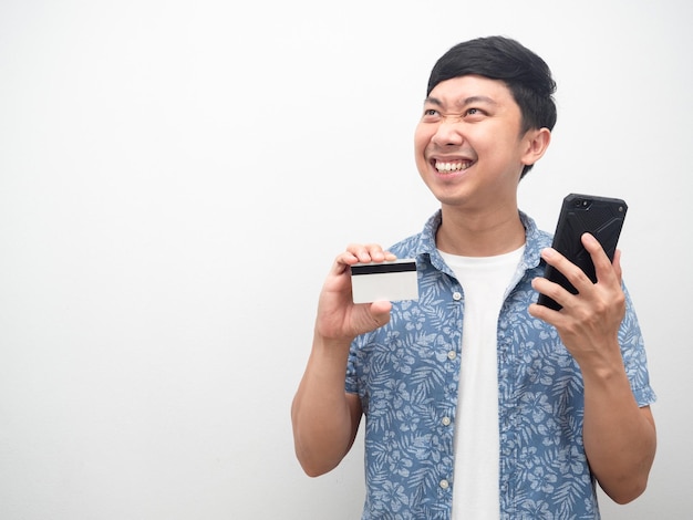 Man showing credit card and mobile phone very happy looking at copy space