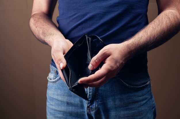 Man showing empty wallet on brown background