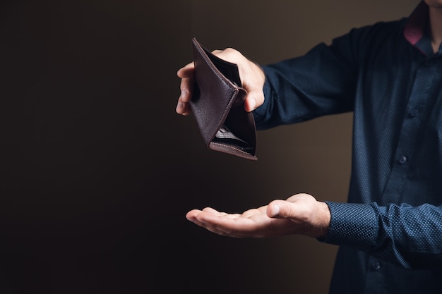 Man showing empty wallet on brown surface