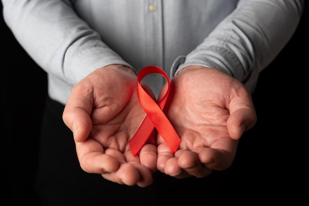 Man showing his two open hands holding red ribbon in support of World AIDS Day empathy hiv patients