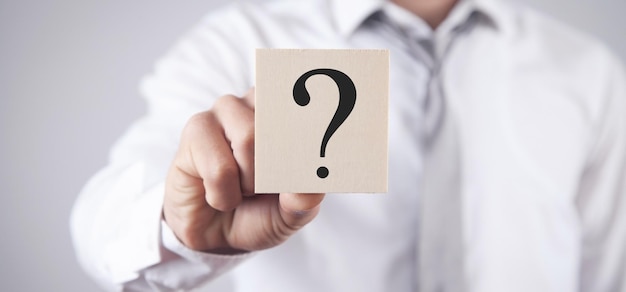 Man showing question mark on wooden cube