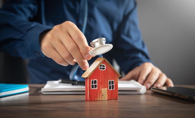 Man showing stethoscope over house model