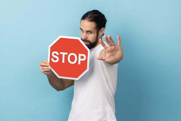 Man showing stop gesture and holding red stop road sign prohibitions and restrictions