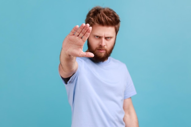 Man showing stop sign standing with frowning face and bossy expression avoid danger