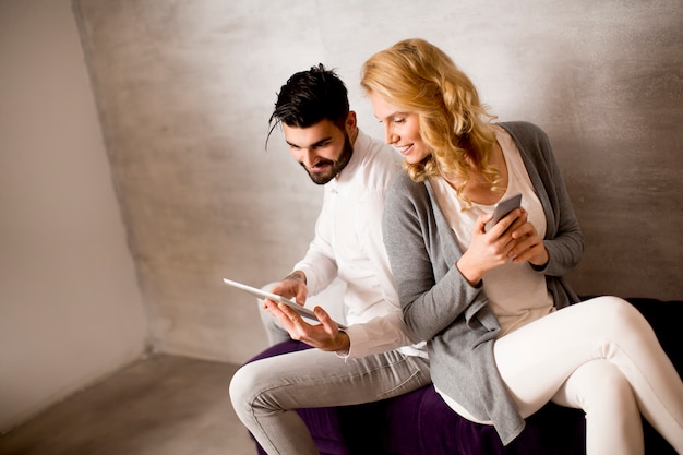 Man showing to young woman information on tablet while she holding smartphone