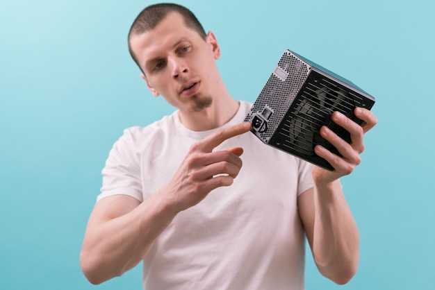 A man shows with a pointing finger at a connector of a computer power supply on a blue background Hand Electricity Electronic Supply Component Connection Hardware Unit Electric