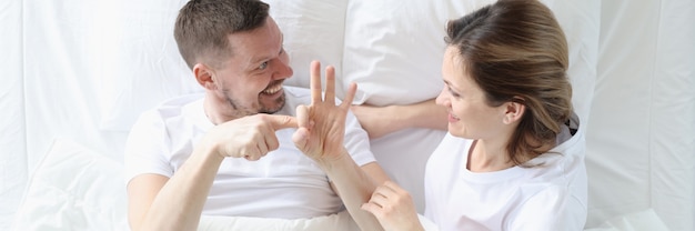 Man shows woman intimate gestures on bed sexual life of partners concept