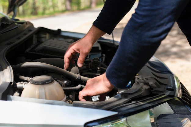 A man on the side of the road is fixing a car Hands on the hood Car repair on the road