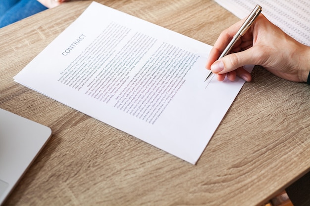 Man signs a contract at a desk in a company office.