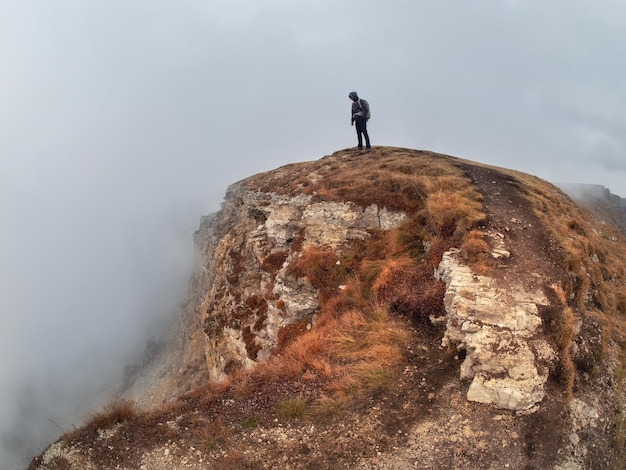 Man silhouette above a misty clouds morning hilly landscape Alone Rock with traveler man above the clouds at the misty morning in Caucasus